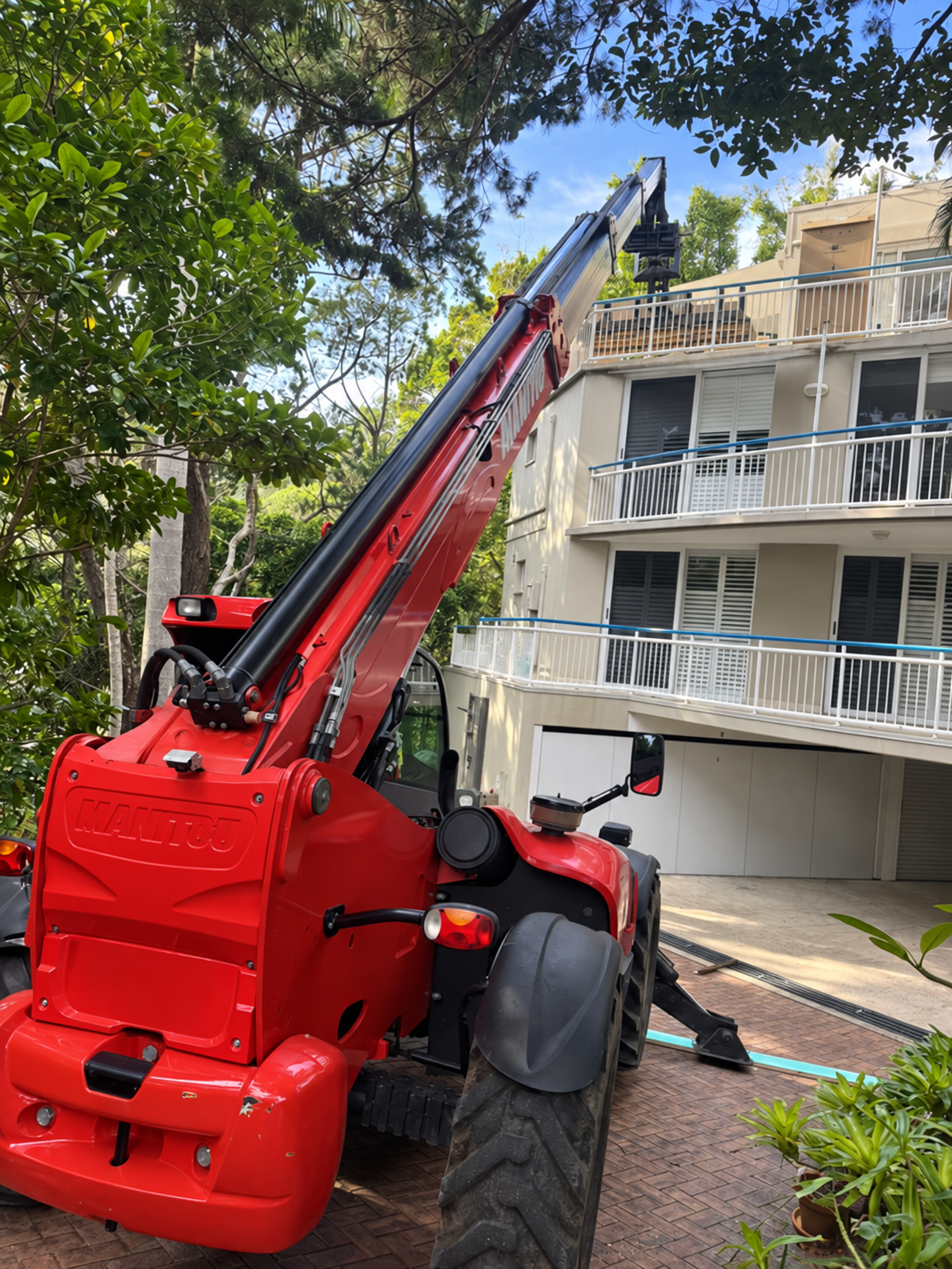Red telehandler positioned for difficult residential access